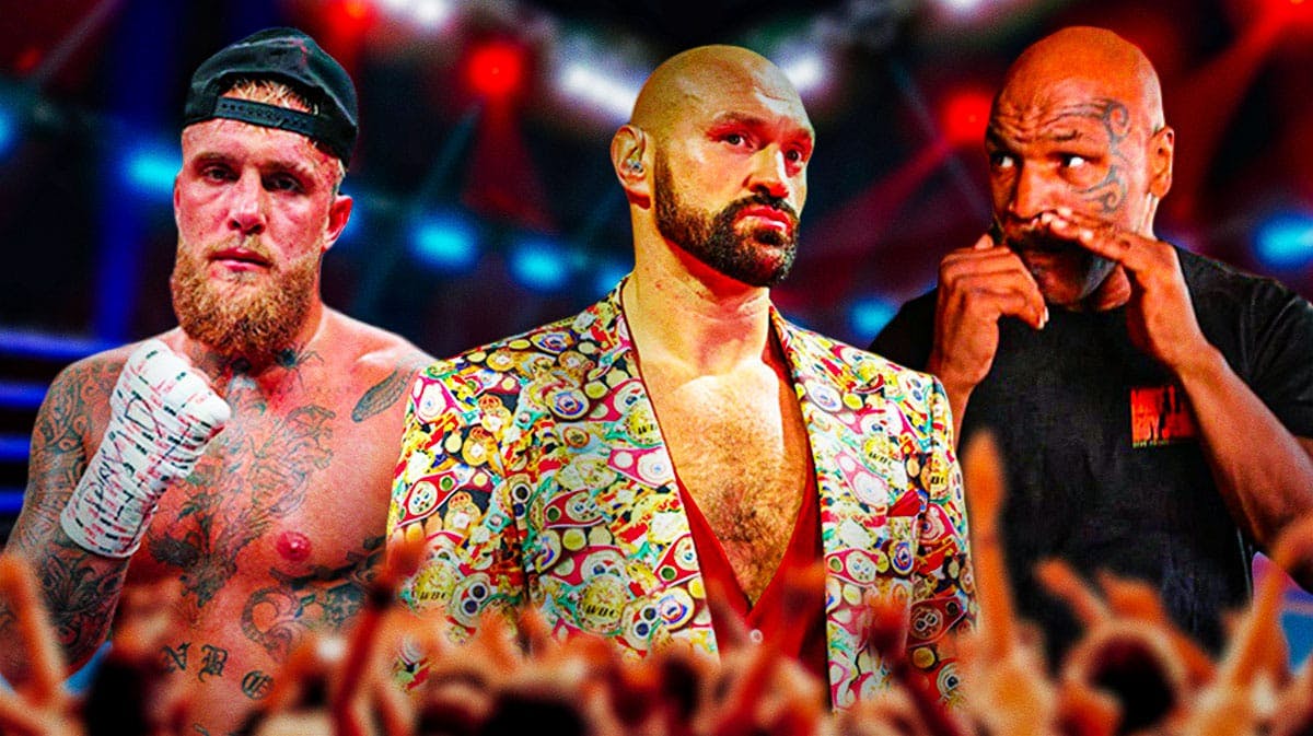 Tyson Fury stands next to and Mike Tyson and Jake Paul in boxing ring