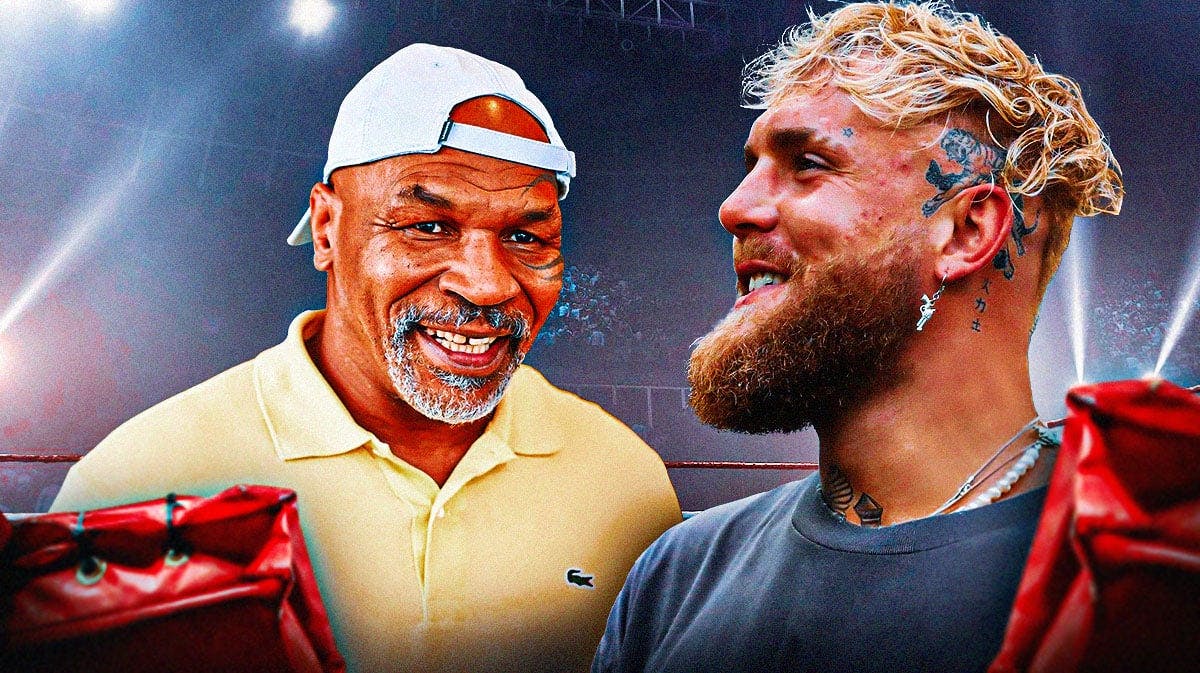 Jake Paul laughing next to Mike Tyson in front of a boxing ring