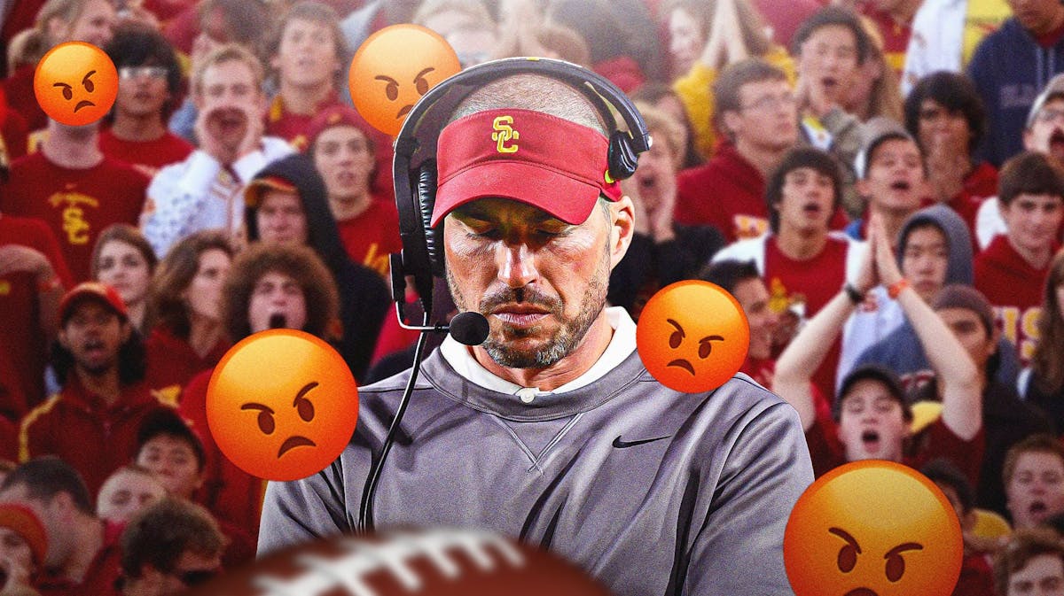 USC defensive coordinator Alex Grinch looks down. Fans in the background yell.