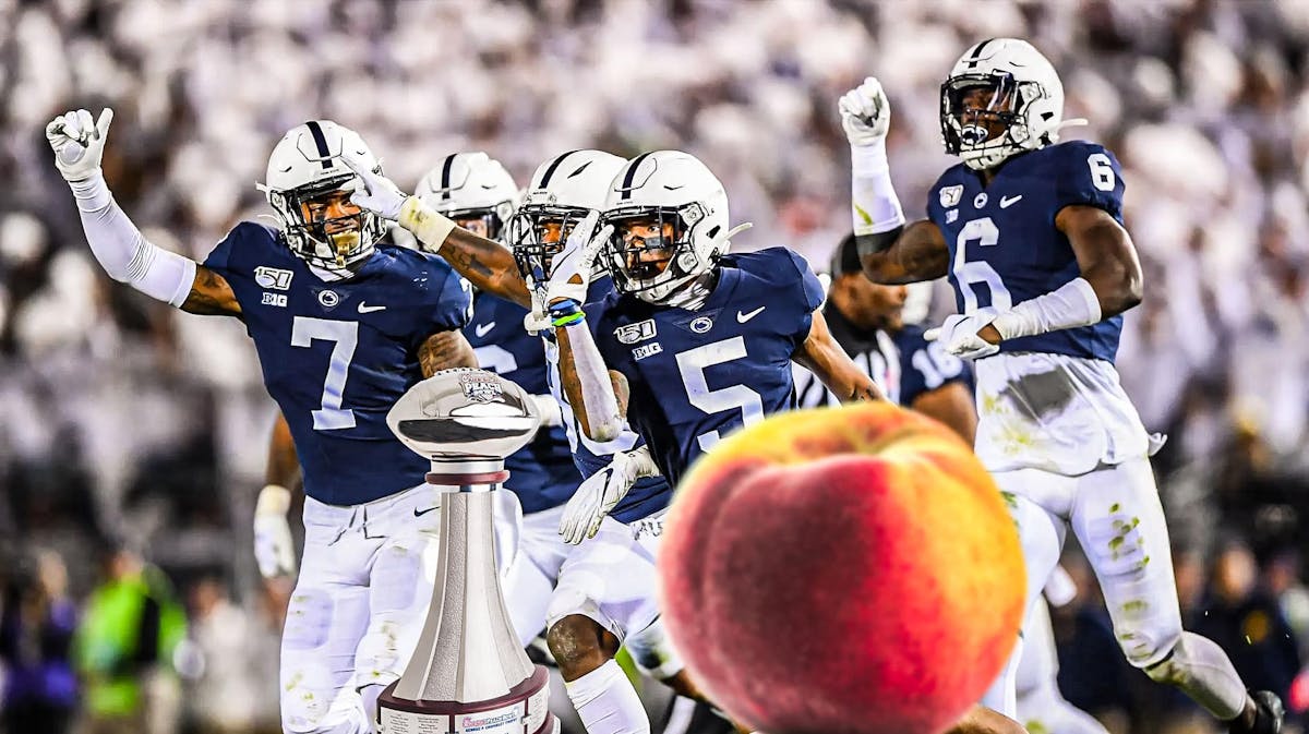 Penn State football players in the background, while in the foreground a peach along with a football trophy.