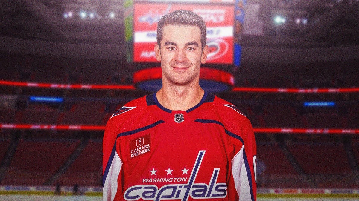 Mac Pacioretty in middle of image looking hopeful in a Washington Capitals jersey, hockey rink in background