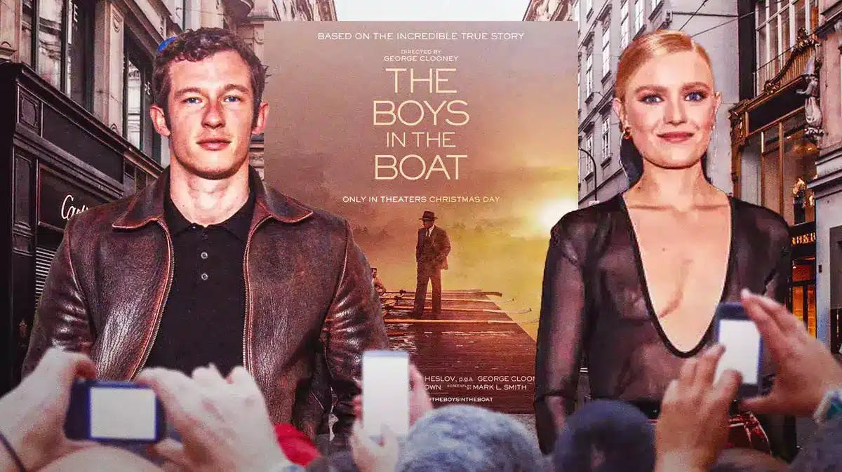 Callum Turner and Hadley Robinson with The Boys in the Boat poster in between them.