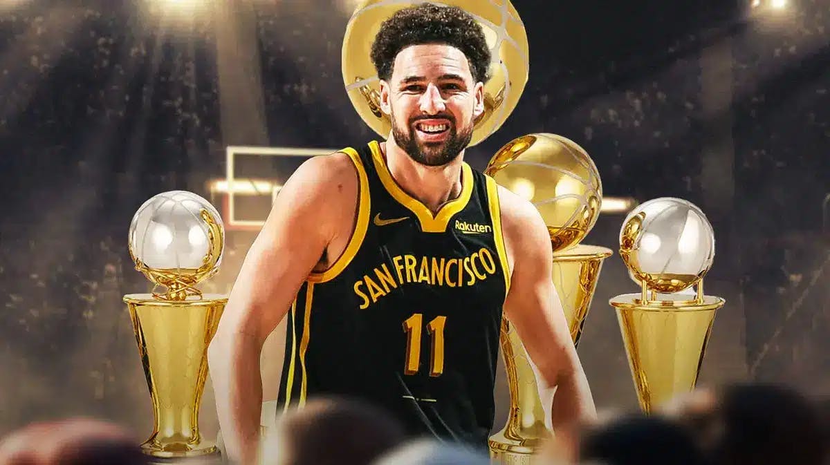 Klay Thompson smiling with four championship trophies at the back