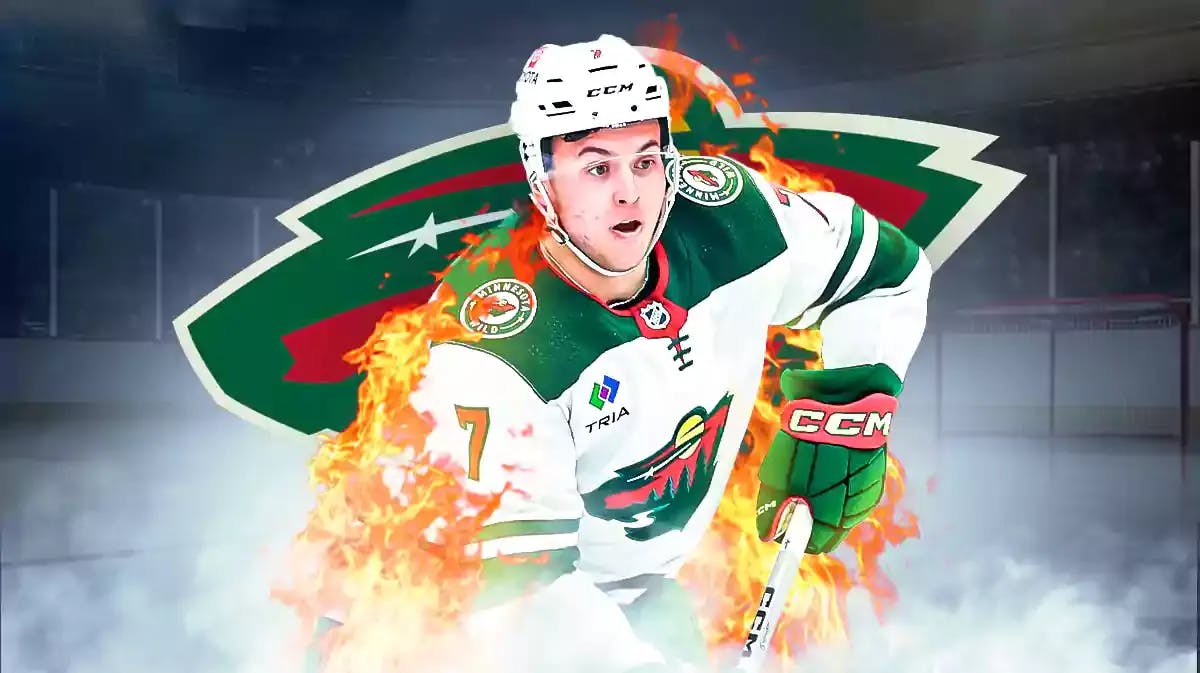 Brock Faber in middle of image looking happy with fire around him, Minnesota Wild logo, hockey rink in background