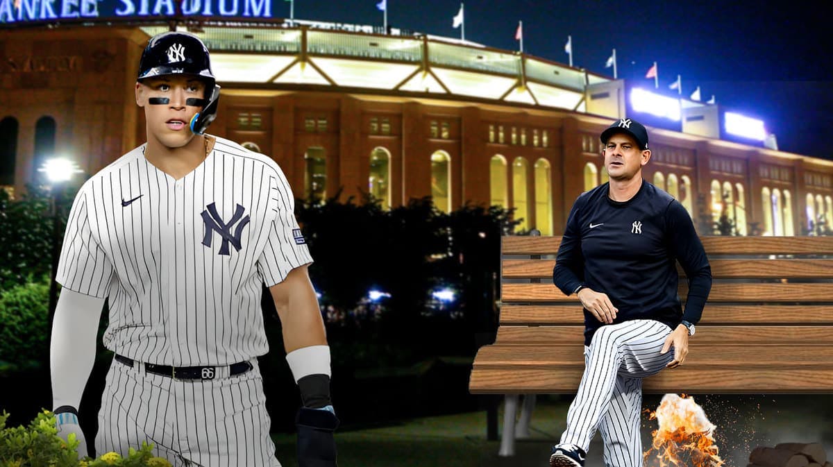 Yankees' Aaron Boone sitting on a chair with a bonfire below the chair, Aaron Judge looking on