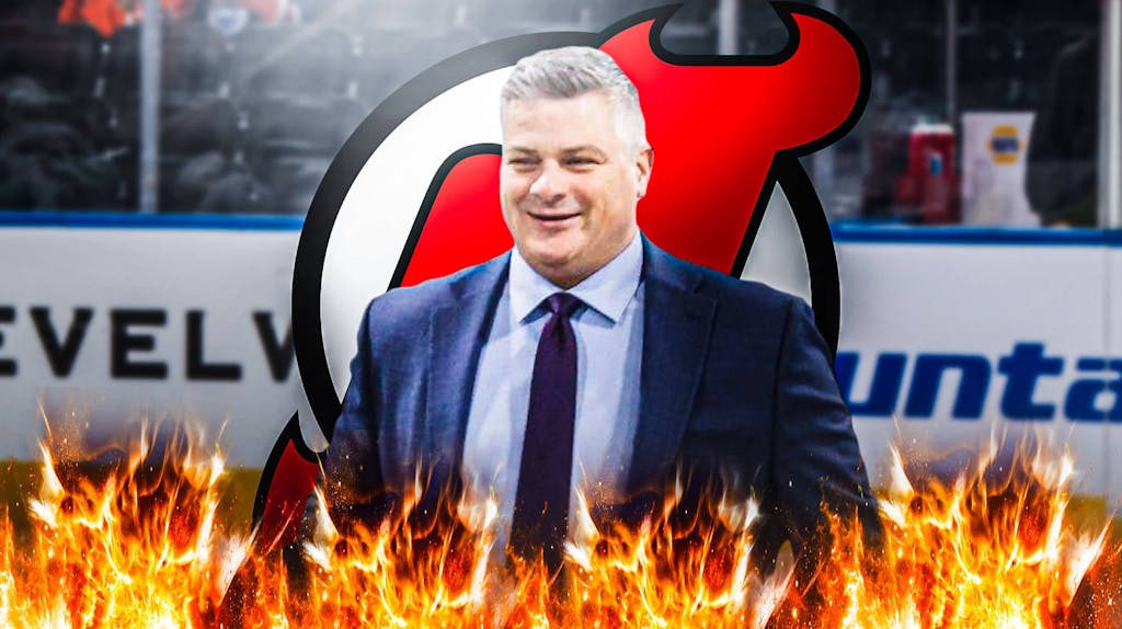 Sheldon Keefe looking happy with fire around him, New Jersey Devils logo, hockey rink in background