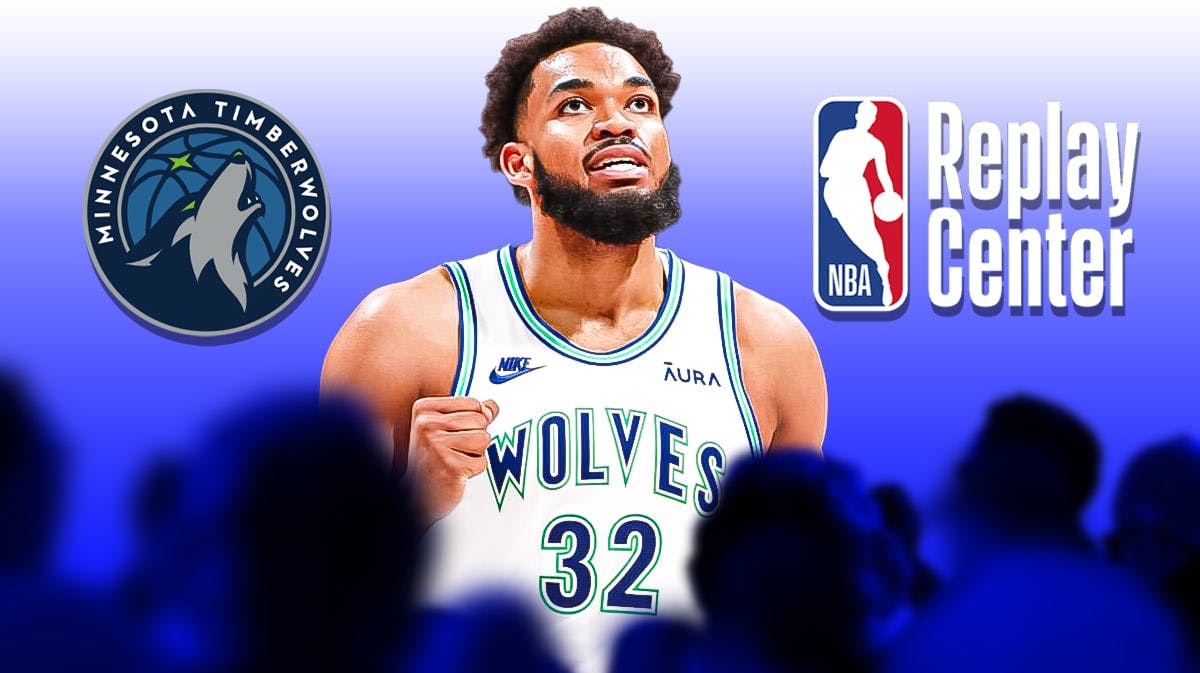 Timberwolves' Karl-Anthony Towns stands next to NBA Replay Center logo with Mavericks fans in background