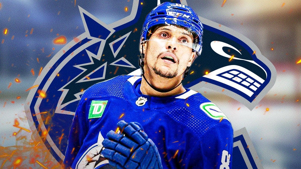 Dakota Joshua in middle of image looking happy with fire around him and money in image, Vancouver Canucks logo, hockey rink in background