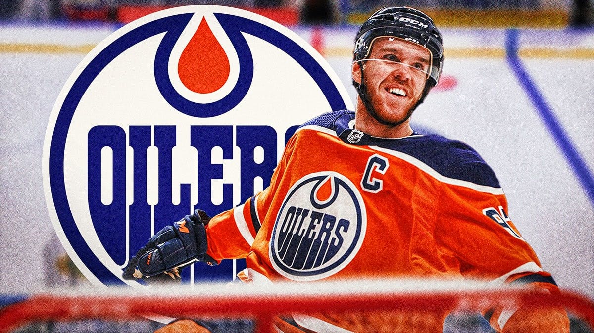 Connor McDavid in middle of image looking happy, Edmonton Oilers logo, hockey rink in background
