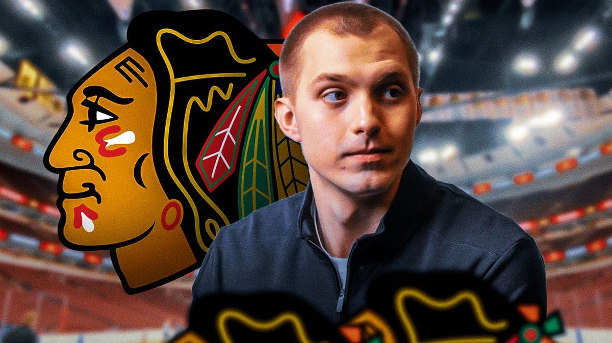 Artyom Levshunov in middle of image looking happy, Chicago Blackhawks logo, hockey rink in background