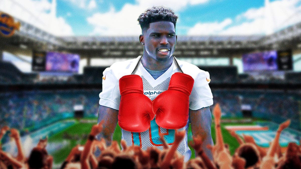 A picture of Tyreek Hill in a Dolphins jersey with boxing gloves around his neck and a football field in the background.