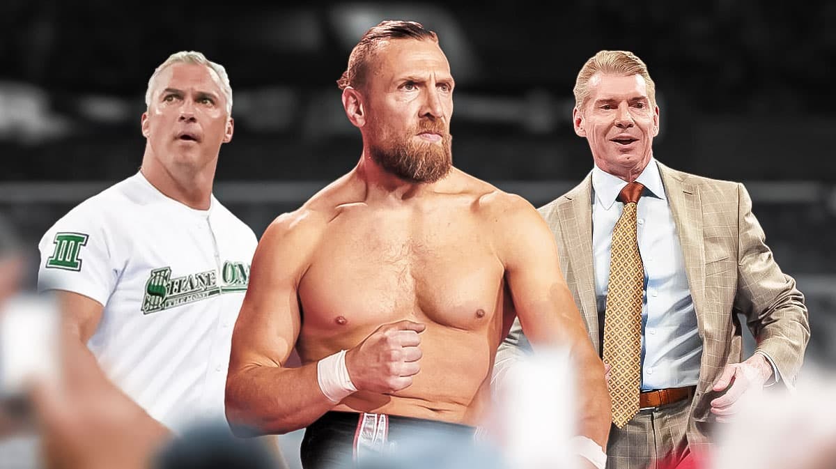 Bryan Danielson with Shane McMahon on his left and Vince McMahon on his right inside a wrestling ring.