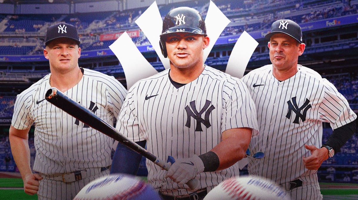 Clarke Schmidt, Jasson Dominguez, and manager Aaron Boone in front of Yankees logo