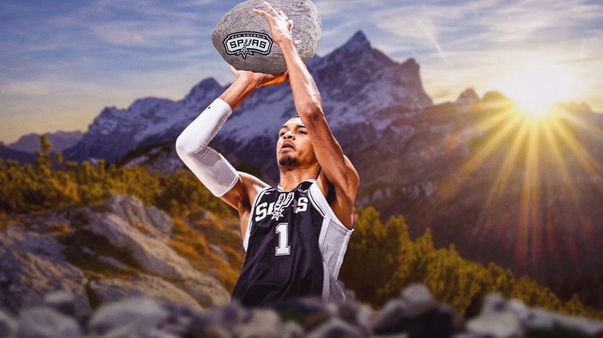 Victor Wembanyama carrying a large boulder of rock with Spurs logo on it