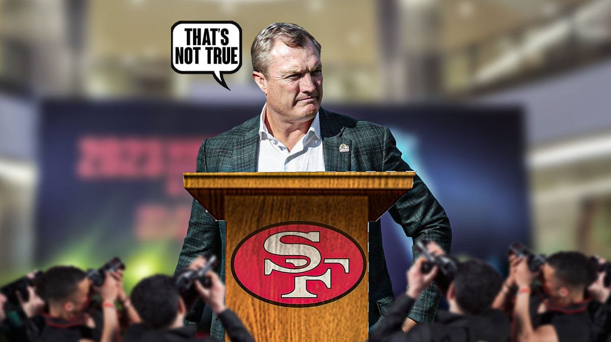 John Lynch at a podium with the 49ers logo on it