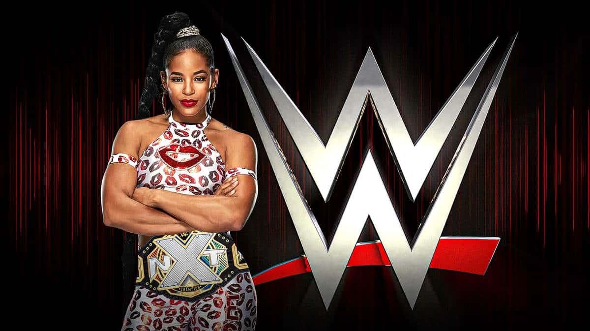 Bianca Belair with the NXT Championship around her waist with the WWE logo as the background.