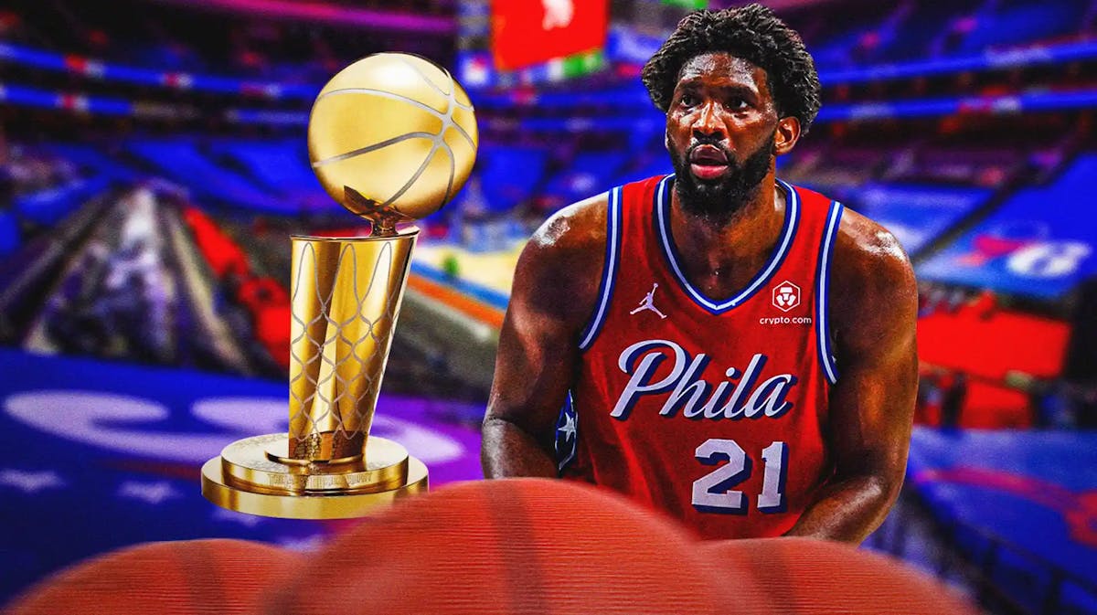 Joel Embiid alongside the NBA trophy with the Sixers arena in the background