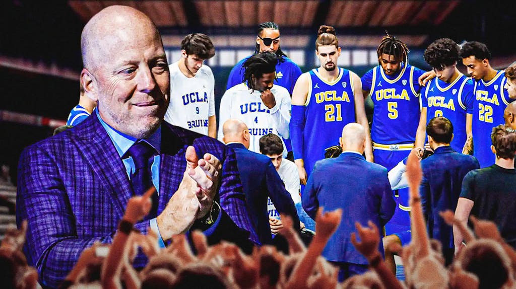 UCLA basketball coach Mick Cronin clapping in joy with UCLA basketball players in background.