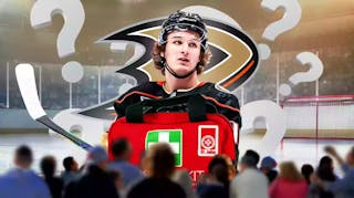 Trevor Zegras in middle of image looking stern, a few question marks around him, first aid kit for injury, ANA Ducks logo, hockey rink in background