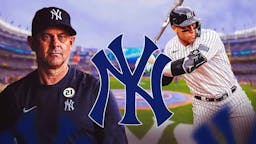 Aaron Boone and Aaron Judge swinging a bat next to a Yankees logo at Yankee Stadium