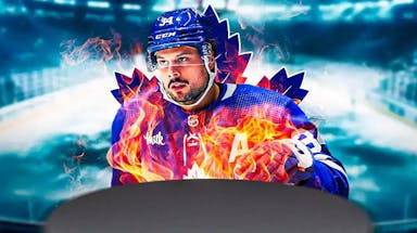 Auston Matthews in middle of image with fire around him looking happy, TOR Maple Leafs logo, hockey rink in background