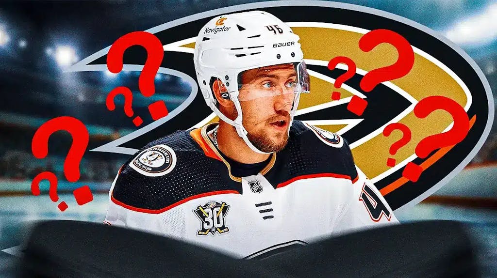 Ilya Lyubushkin in middle of image looking stern, ANA Ducks logo, 3-5 question marks, hockey rink in background