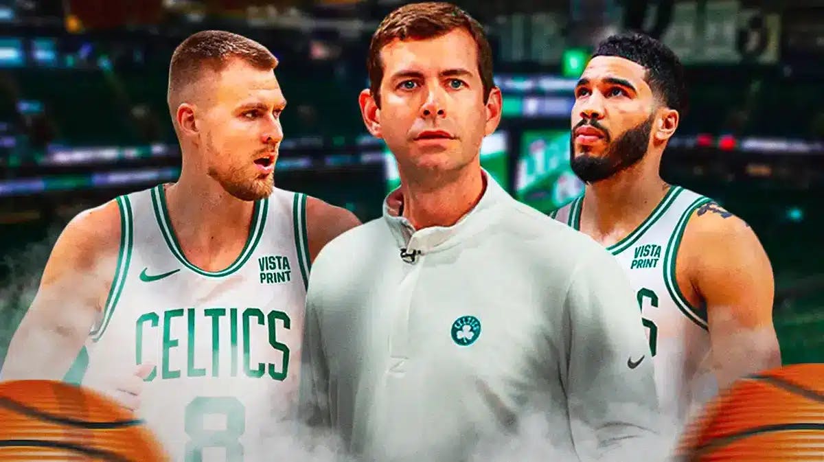 Brad Stevens in the middle of the image with Kristaps Porzingis to his right and Jayson Tatum to his left. They’re all looking somewhat serious and they’re on a Boston city skyline background