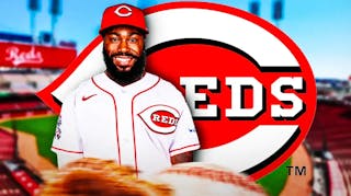 Josh Harrison wearing a Reds jersey in front of a Reds logo at Great American Ball Park