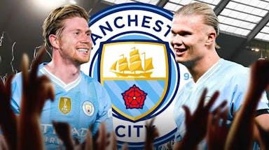 Kevin De Bruyne laughing with Erling Haaland in front of the Manchester City logo