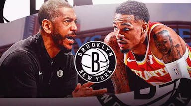 Nets Kevin Ollie looking at Hawks Dejounte Murray with a Nets logo between them at Barclays Center