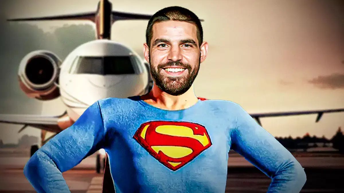 Raven’s Mark Andrews with a Superman cape on and a Superman S on his chest with an airplane on a runway in the background.
