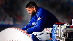 Blue Jays' Alek Manoah looking upset and sitting in an MLB dugout.