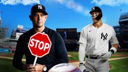 Yankees' Aaron Boone holding a stop sign. Yankees' Aaron Judge in background looking serious.