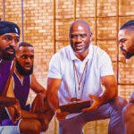 Magic Johnson holding a coaching board with the faces of D'Angelo Russell, Gabe Vincent, Austin Reaves and D'Angelo Russell on it. LeBron James looking serious