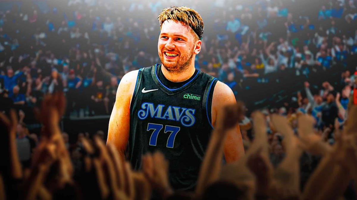 Mavericks' Luka Doncic smiling at the American Airlines Center. In background, need Mavericks fans cheering at the American Airlines Center.