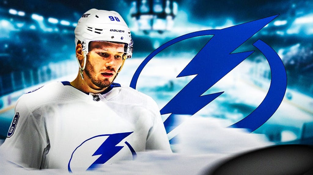 Mikhail Sergachev in middle of image looking hopeful, Tampa Bay Lightning logo, hockey rink in background