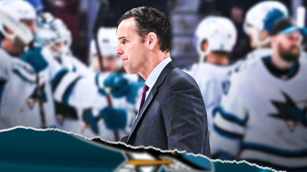 Sharks coach David Quinn stands in front of scoreboard record, Stanley Cup Playoffs fans in background